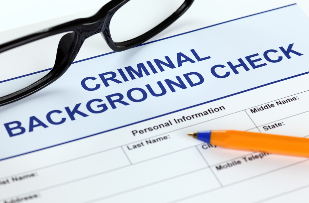 A criminal background check document, glasses, and a pen