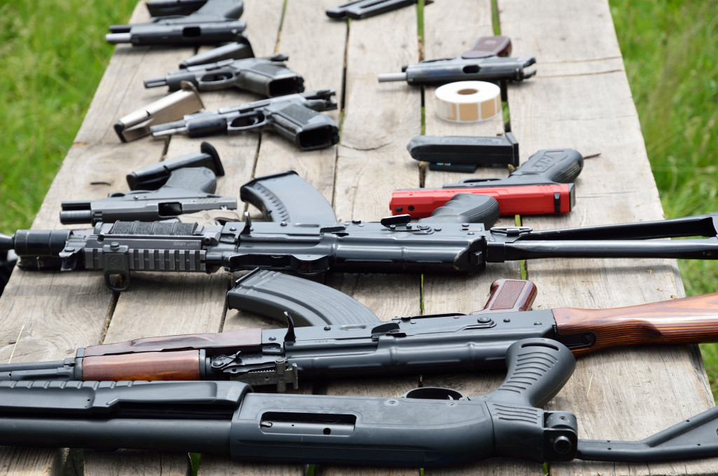 Various firearms on a wooden table outdoors