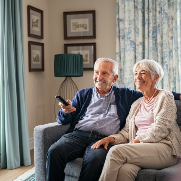 Seniors watch TV for entertainment while man using remote control.